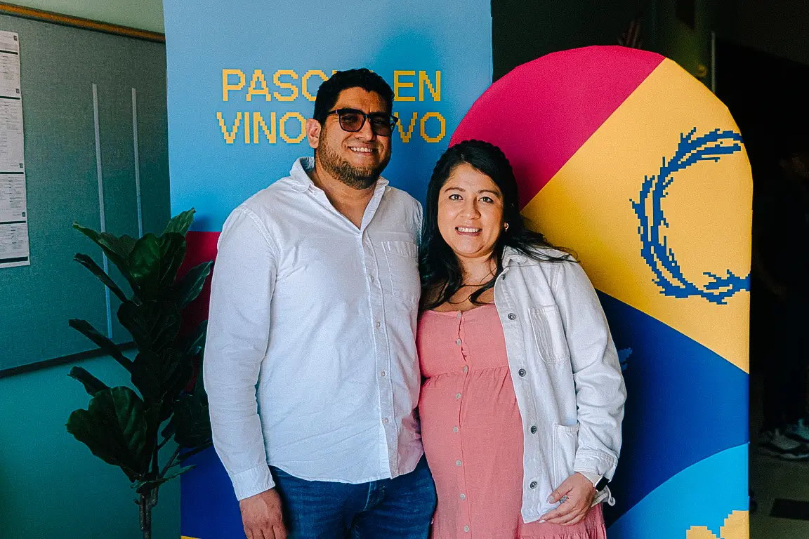 Pareja frente a banner de Pascua en Vino Nuevo, sonrientes y posando juntos.